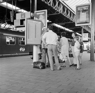 881998 Afbeelding van treinreizigers bij het vertrektijdenbord op het perron van het N.S.-station Eindhoven te Eindhoven.